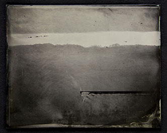 C2: Landscape photo on glass becomes field of warm/cool tonal ranges. Warm grey on top. Dark grey dominates below. Demarcated by a silver streak