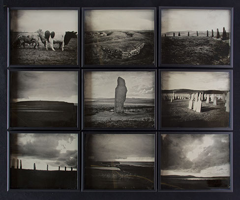 A 3x3 grid of glass photographs on black velvet in matte black frames. Depict Orkney landscapes of grassy hills, monoliths, cows, graves & shore
