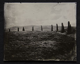 Panel A3 is a phot on glass depicting a grassy mound decorated with stone megaliths surrounding its border in the distance. A sky glows above.