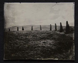 Panel A3 is a phot on glass depicting a grassy mound decorated with stone megaliths surrounding its border in the distance. A sky glows above.