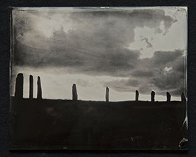 Panel C1 depicts a low landscape in silouette topped with monoliths surrounded by bright sky with dark rolling clouds above.